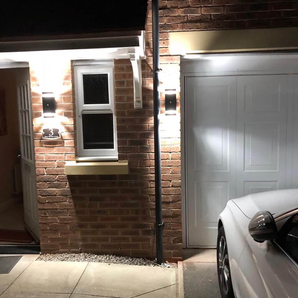 Up-and-down wall lights on brickwork beside a garage and front door