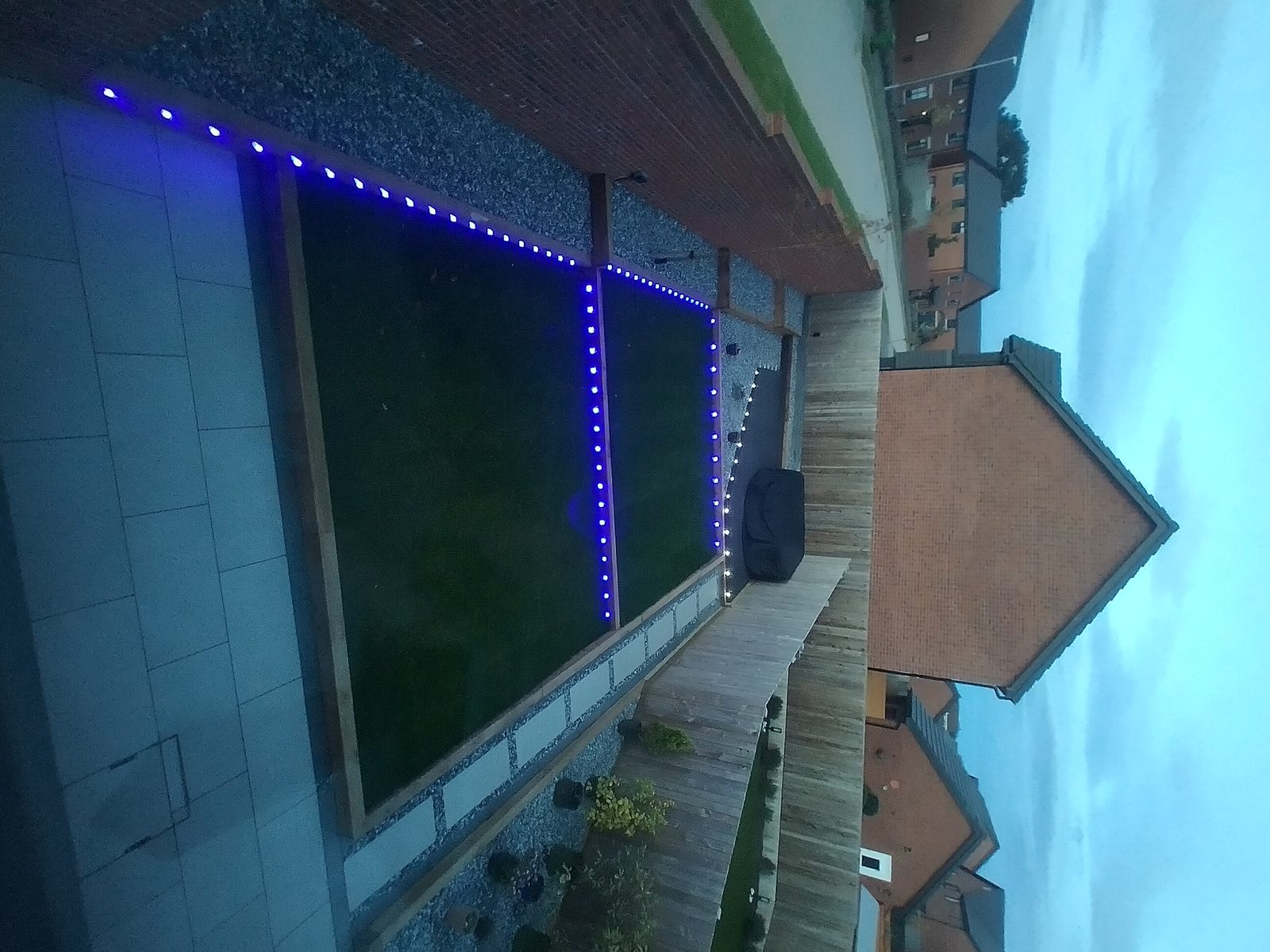 Evening garden with blue LED border lights along timber lawn edges